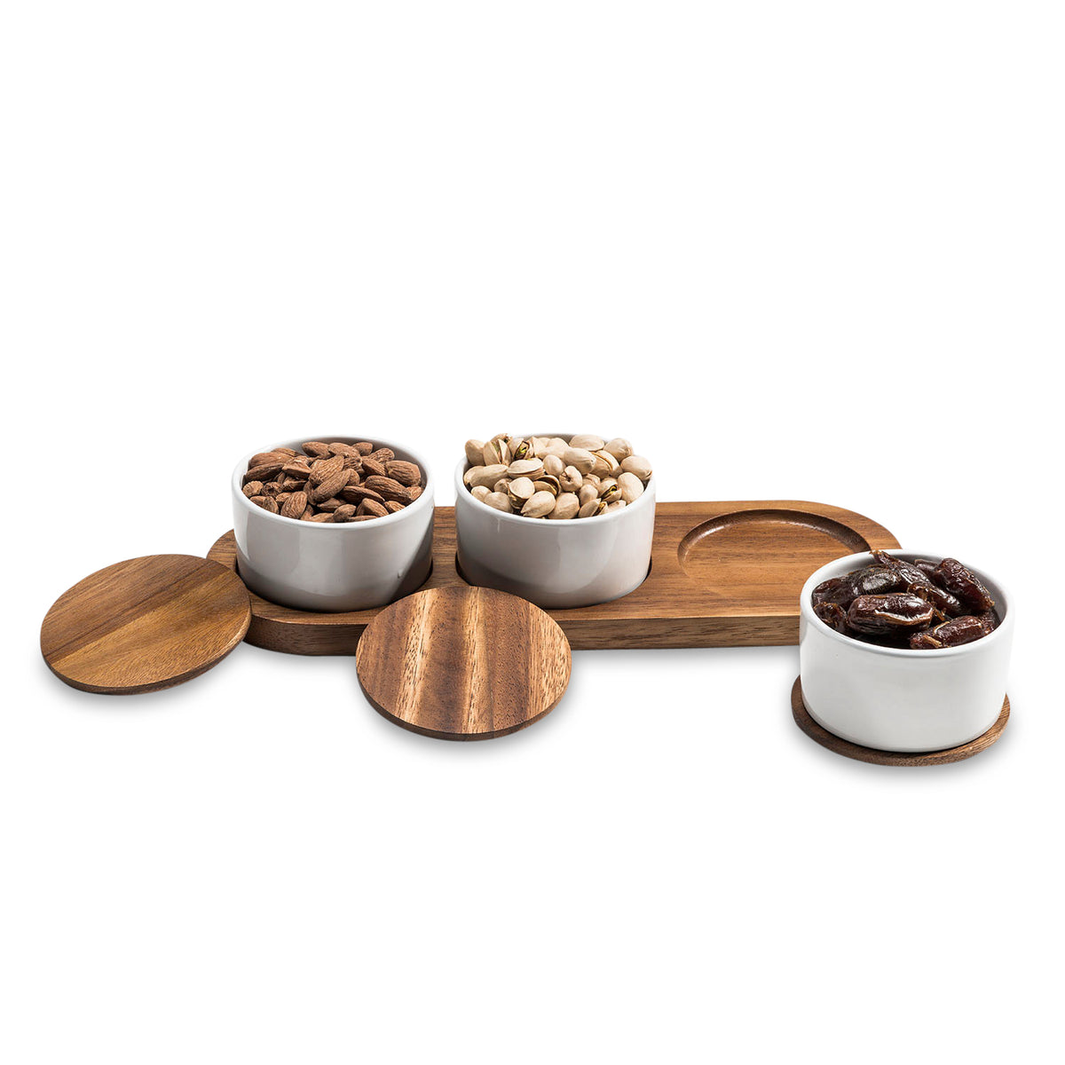 Three white bowls with wooden lids containing different types of nuts